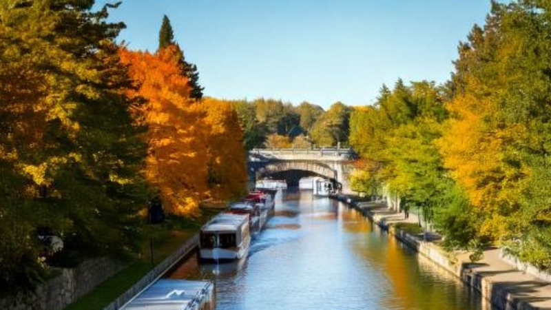 Wide shot of Rideau Canal with boats passing below the bridge